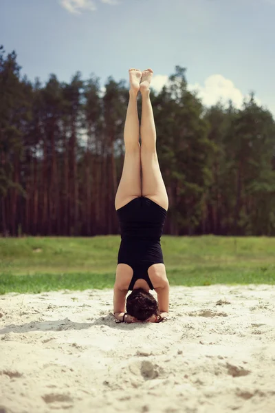 Beautiful girl is engaged in yoga in the forest on the sand — Stock Photo, Image