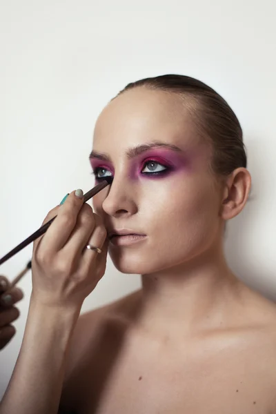 Makeup artist applies eye shadow. Beautiful woman face. Perfect makeup