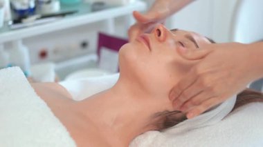Kadın, spa salonundaki terapistinden nazikçe yüz masajı alıyor. Cilt sağlığı, rahatlama ve gençleşme için sakin ve yetenekli dokunuşlar kullanıyor.