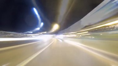 Şehir ışıklarından ve geçen araçlardan gelen bulanık ışık izlerini göstererek gece yolundaki araba yolculuğunun hızlandırılması dinamik bir görsel etki yaratıyor.