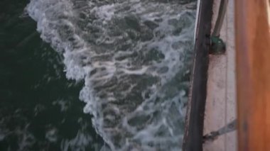 Alacakaranlıkta sakin bir göle yelken açarak, kayık suda süzülür, hafif dalgalar oluşturarak, akşamın sakin havasını yansıtır..