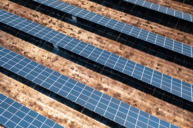 Güneşli bir günde kırsal alanlardaki sıra sıra güneş panellerinin yüksek açılı görüntüsü, temiz enerjiden yararlanmak ve sakin ve açık arazide sürdürülebilir tarım uygulamalarını yansıtmak