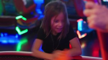 Atari masasında hokey oynayan, eğlence yarışmasının ve eğlence merkezinde parlayan çevrenin tadını çıkaran bir kız.