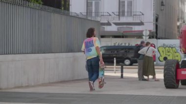 Portekiz, Lizbon 25 Haziran 2025 Bir Lizbon caddesinde iki kişi birbirine yaklaşırken ayak sesleri yankılanıyor. Etkileşimler makine ve renkli graffiti yakınlarında gerçekleştikçe atmosfer değişiyor..