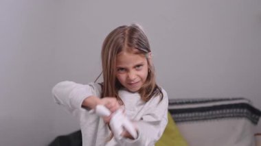 Yaramaz kız kâğıtları yırtıp evdeki havaya fırlatıyor yüzsüz bir ifadeyle eğlenceli bir şekilde eğleniyor.