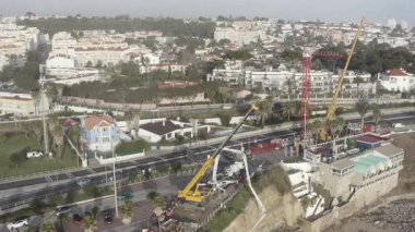 Sahil şeridi dengeleme çalışmalarının insansız hava aracı görüntüleri, yoğun şehir trafiği boyunca inşaat araçlarıyla çalışarak kıyı şeridi yakınlarındaki kentsel kalkınma ve altyapı çabalarını vurguluyor