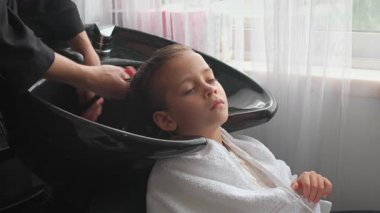 Yetenekli bir kuaför küçük kızların saçlarını dikkatlice yıkar ve rahatlatıcı bir deneyim yaratır. Güneş ışığı çağlayan sular gibi akar ve anı özel kılar..