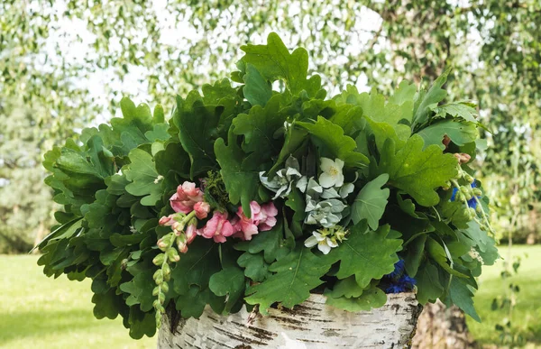 summer solstice wreath of oak branches and flowers on a birch block