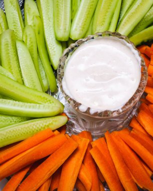 Tabağın ortasında dilimlenmiş taze havuç ve salatalık var.