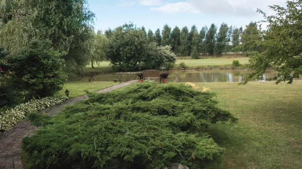 중앙에 연못의 포장도로는 강변에 나무로 벤치로 이어진다 — 스톡 사진