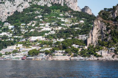 Capri, İtalya - 04.29.2025: Yamaçta kayalıklar ve evler inşa edilmiş güzel adanın genel manzarası.