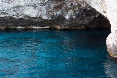 Capri, İtalya - 04.29.2025: Capri Adası 'ndaki bir mağaranın ön görüntüsü; mağaranın yakınındaki açık mavi deniz suyu çok güzel aydınlatılmış..