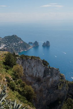 Capri, İtalya - 04.29.2025: Adanın en yüksek noktasından deniz manzaralı ünlü Faraglioni kaya yığınları. Uzakta sis var..