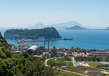 Napoli, İtalya - 05.01.2025: Nisida adası ve kıyı bölgesinde terk edilmiş Bagnoli sanayisi ile Napoli Körfezi 'nin manzarası, evler ve liman rıhtımı; uzak mesafede gizlenmiş dağlar.