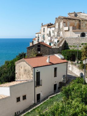 Sperlonga, İtalya - 05.02.2025: Tepedeki eski binalar ve Sperlonga kasabasındaki dar bir yaya sokağı. Denizin mavi suları ve berrak mavi gökyüzü.