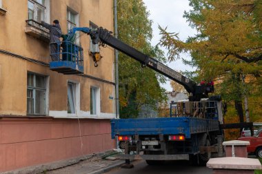 Asansördeki işçiler binanın ön cephesini onarıyor.