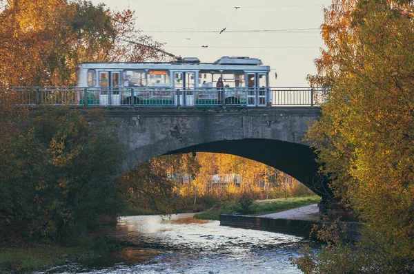 Autumn landscape with woman on the bridge and passing trolley bus in motion blur — Stock Photo, Image