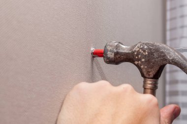 Gri duvardaki bir deliğe plastik bir delik açıyor.