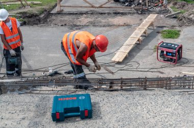 Turuncu yelekli işçiler beton merdivenleri onarıyor.