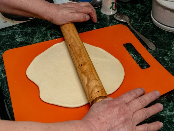 Close-up of a wooden rolling pin on a piece of raw dough — Stock Photo, Image