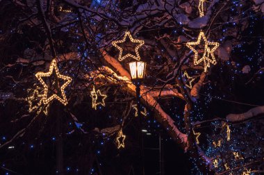 Kış gecesi arka planı sokak lambası ve yıldız şeklinde parıldayan süslemelerle dolu. Yüksek kalite fotoğraf