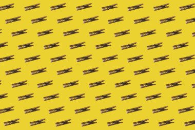 Sarı arka planda eski ahşap mandallardan yapılmış yaratıcı desen