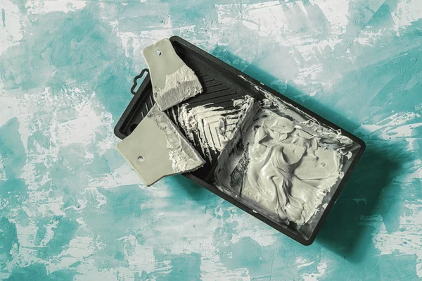 Turkuaz beton arka planda iki spatula ile boya tepsisi.