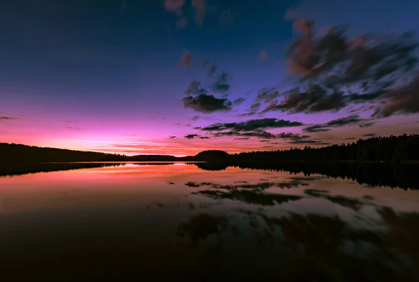 Hermoso paisaje nocturno con puesta de sol sobre el lago y nubes reflejadas en el agua — Foto de Stock