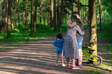 Parkta çocuklu genç bir aile bir arada duruyor. Arkadan bak. Yüksek kalite fotoğraf