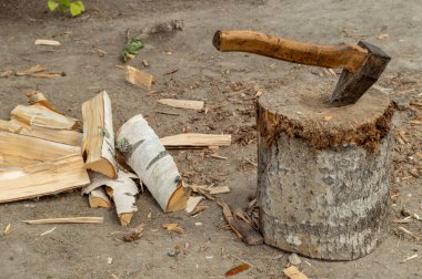 Tahta bir güvertede, huş ağacının yanında sıkışmış bir balta. Yüksek kalite fotoğraf