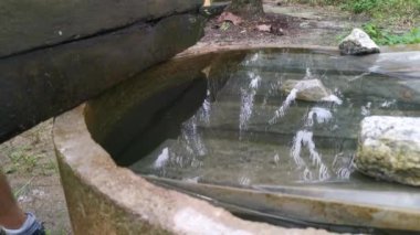 Su dolu beton kuyunun üzerinde yıkanan elin görüntüleri.