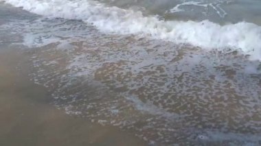 Deniz dalgasının kumlu sahile doğru ilerleyişinin gündüz görüntüsü.