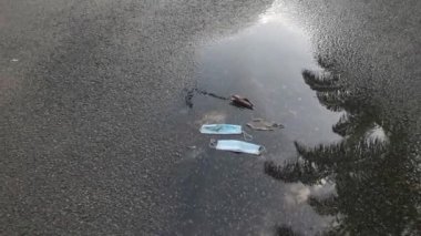 Ameliyat maskesiyle su birikintisinin etrafındaki sokak manzarası.