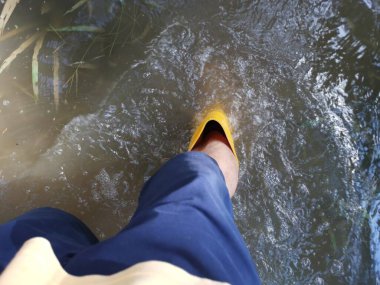 Bilinmeyen kişi sarı çizme giyiyor, sel basmış çiftliğe doğru yürüyor..