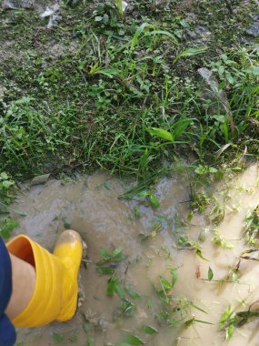 Bilinmeyen kişi sarı çizme giyiyor, sel basmış çiftliğe doğru yürüyor..
