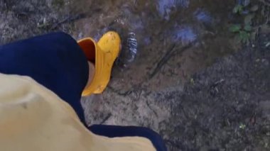 Bilinmeyen kişi sarı çizme giyiyor, sel basmış çiftliğe doğru yürüyor..