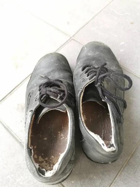 worn out man\'s black leather shoe.