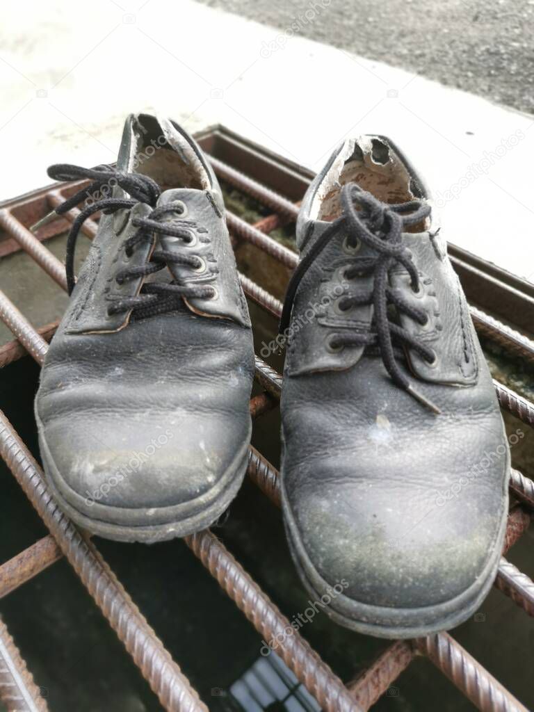 worn out man's black leather shoe.