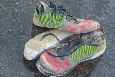 Yol kenarındaki su birikintisinde yıpranmış spor ayakkabı ve çorap..