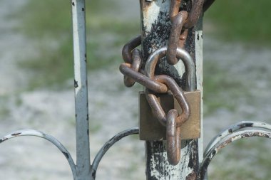 Giriş kapısında paslı metal zincir ve asma kilit var..