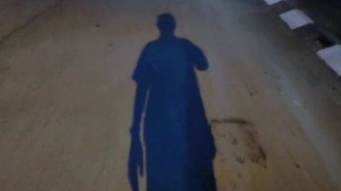 Geceleri sokakta yürüyen tanınmayan birinin gölgesi..