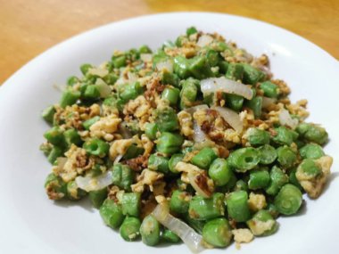 Yumurta ve dilimlenmiş soğanla kızartılmış uzun fasulyeli sebze.