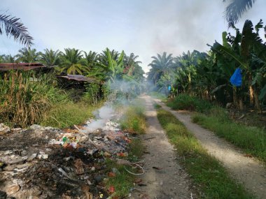 Kırsal yol boyunca yanan çöpler..
