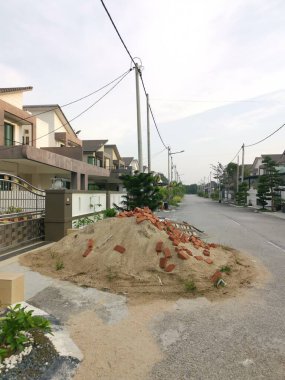 Kum yığını, kırmızı tuğla ve çakıl taşı tadilat altındaki evin dışında bulundu..