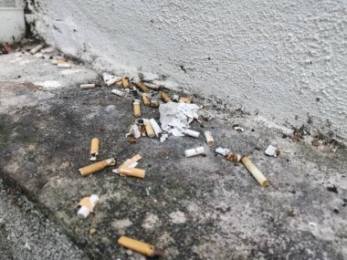 Kirli su giderinin köşesinde sigara izmaritleri var..