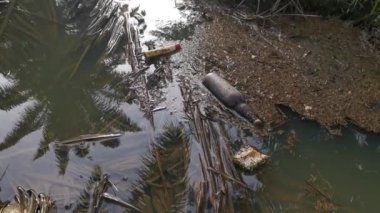 Kirli su yüzeyinde yüzen öğütülmüş siyah cam şişe.