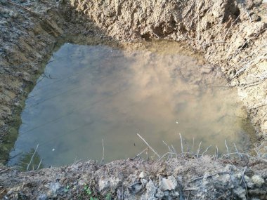 Traktör karada yağmur suyu dolu bir hendek kazdı.