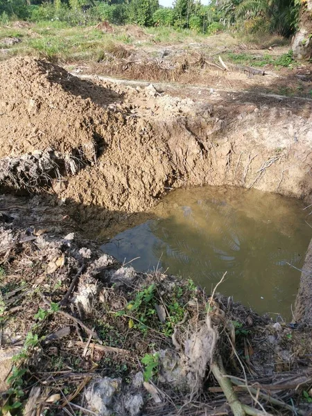 拖拉机在地上挖了一条充满雨水的沟渠 — 图库照片