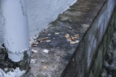 Kirli su giderinin köşesinde sigara izmaritleri var..