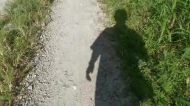 Kırsal yolda yürüyen bir kişinin gölgeli figürü